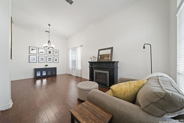 living room featuring an inviting chandelier, crown molding, and dark wood-type flooring