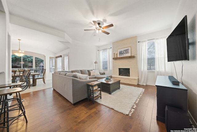 living room featuring dark wood-type flooring, ceiling fan, a fireplace, and plenty of natural light