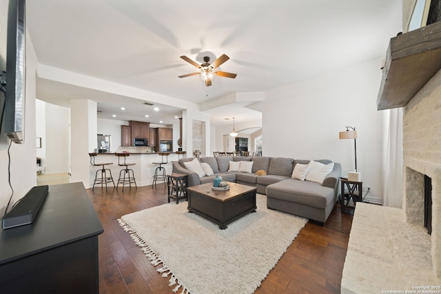 living room featuring ceiling fan, dark wood-type flooring, and a fireplace