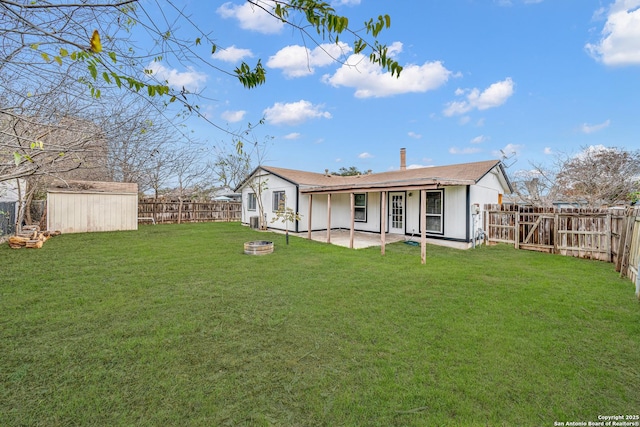 rear view of property with a patio, a lawn, a fire pit, and a storage shed