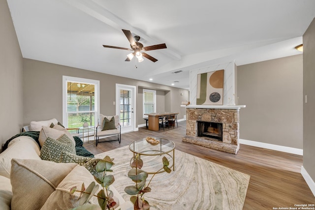 living room with ceiling fan, lofted ceiling with beams, a fireplace, and wood-type flooring