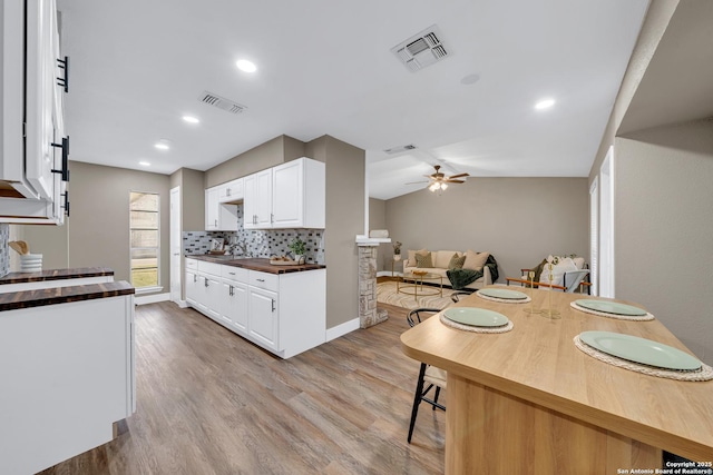 kitchen featuring ceiling fan, white cabinetry, light wood-type flooring, and decorative backsplash