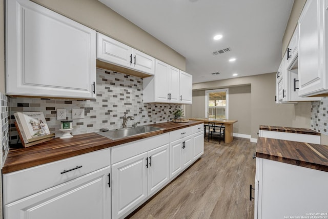 kitchen featuring sink, white cabinetry, wood counters, and light hardwood / wood-style floors