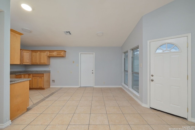 kitchen featuring vaulted ceiling, light brown cabinetry, and light tile patterned flooring