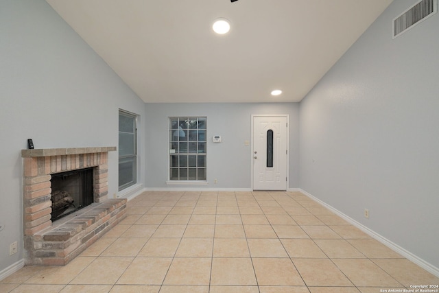 tiled foyer featuring a brick fireplace and vaulted ceiling