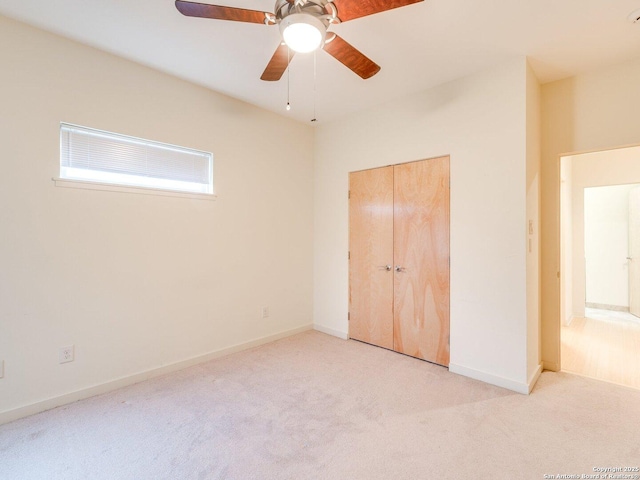 unfurnished bedroom with ceiling fan, light colored carpet, and a closet