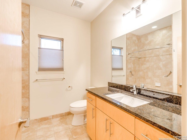 bathroom with toilet, a shower, vanity, and tile patterned floors