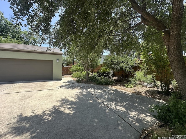 1506 W Mistletoe Ave, San Antonio, TX 78201 - view of side of property with driveway, metal roof, stucco siding, and fence