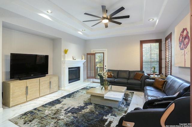 living room featuring ceiling fan and a tray ceiling