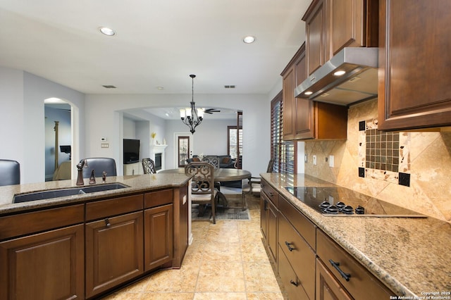 kitchen featuring sink, light stone counters, decorative light fixtures, black electric stovetop, and backsplash