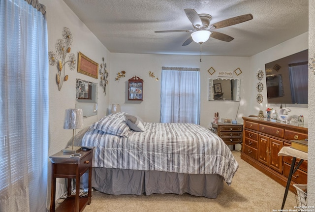 bedroom with light colored carpet, ceiling fan, and a textured ceiling