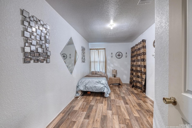 bedroom featuring wood-type flooring and a textured ceiling