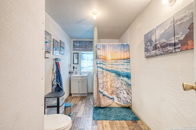 bathroom with hardwood / wood-style floors, toilet, a shower with shower curtain, vanity, and a textured ceiling