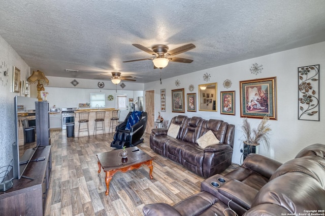 living room with sink, a textured ceiling, ceiling fan, and hardwood / wood-style floors