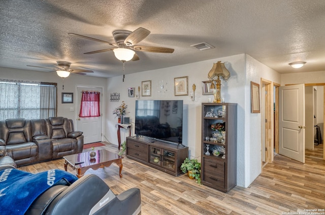 living room with a textured ceiling, ceiling fan, and light hardwood / wood-style floors