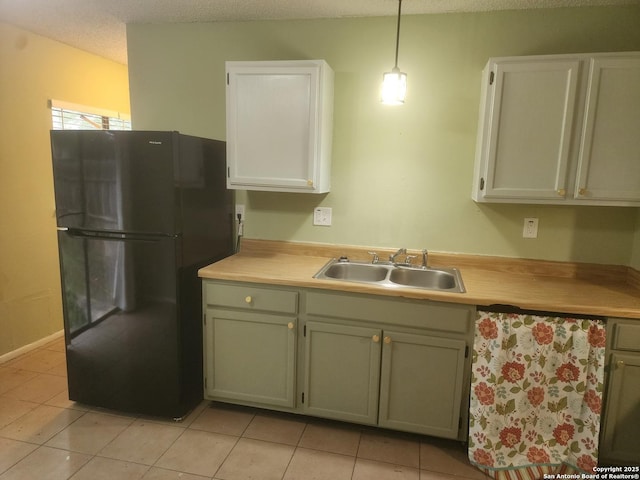 kitchen featuring sink, hanging light fixtures, black refrigerator, and light tile patterned floors