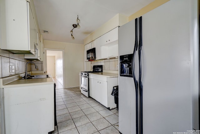 kitchen featuring white cabinetry, light tile patterned flooring, stainless steel gas stove, white fridge with ice dispenser, and sink