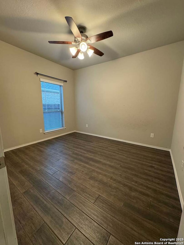 empty room featuring ceiling fan, dark wood-type flooring, and a textured ceiling