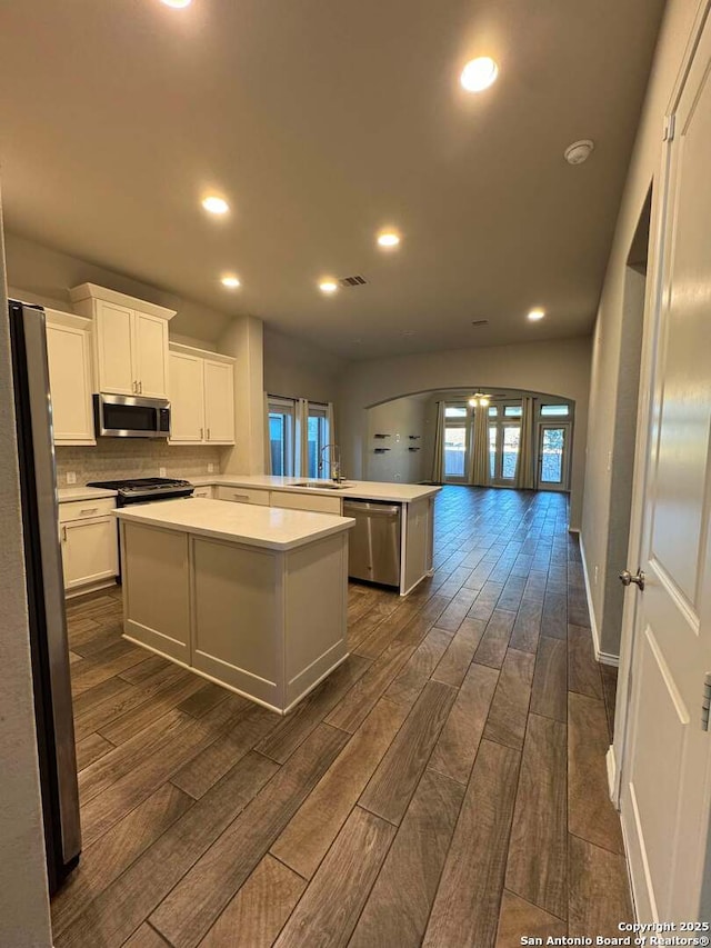 kitchen with kitchen peninsula, stainless steel appliances, french doors, a kitchen island, and white cabinets