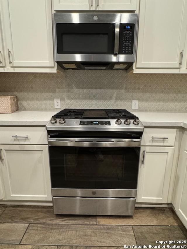 kitchen featuring appliances with stainless steel finishes, decorative backsplash, and white cabinets