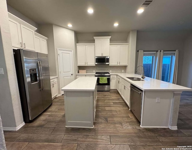 kitchen featuring white cabinetry, stainless steel appliances, a center island, and sink