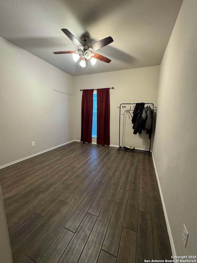 empty room with ceiling fan, dark hardwood / wood-style floors, and a textured ceiling