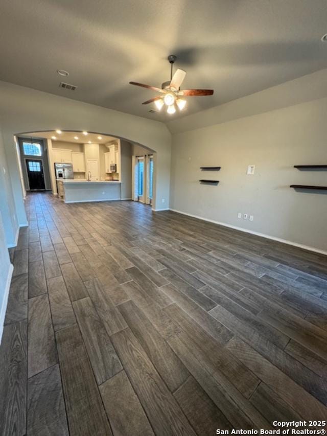 unfurnished living room featuring ceiling fan, dark wood-type flooring, and vaulted ceiling