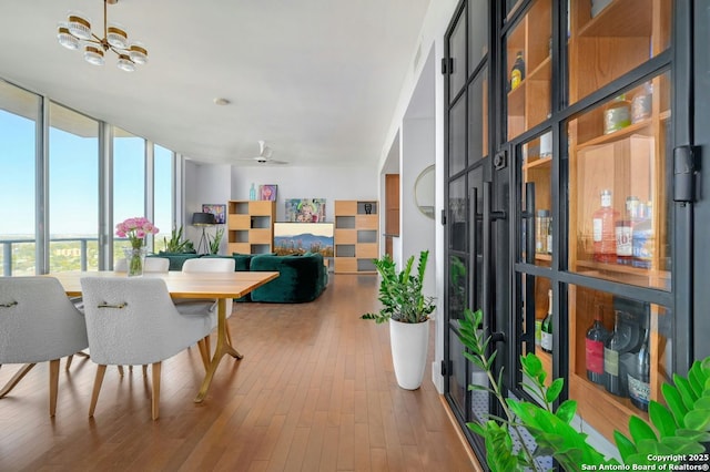 dining space featuring ceiling fan, a wall of windows, and hardwood / wood-style flooring