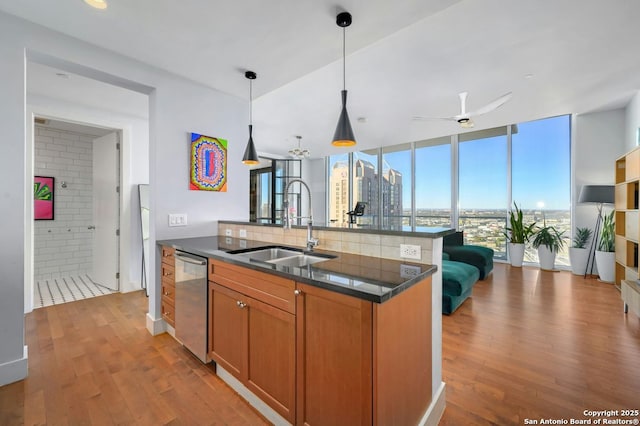 kitchen featuring ceiling fan, stainless steel dishwasher, sink, hanging light fixtures, and a wall of windows