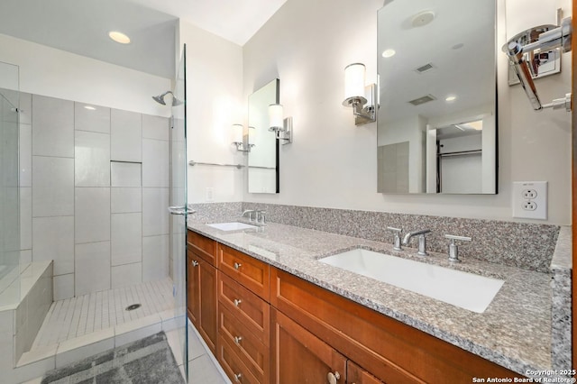 bathroom featuring tile patterned flooring, tiled shower, and vanity