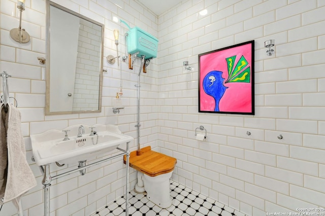 bathroom featuring toilet, tile patterned flooring, tile walls, and sink