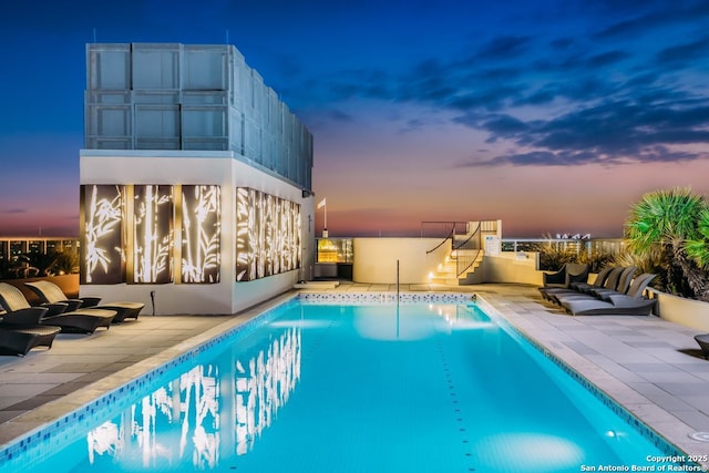 pool at dusk with a patio area