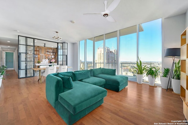 living room with floor to ceiling windows, hardwood / wood-style flooring, and ceiling fan with notable chandelier