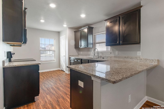 kitchen with light stone counters, plenty of natural light, dark hardwood / wood-style floors, and kitchen peninsula