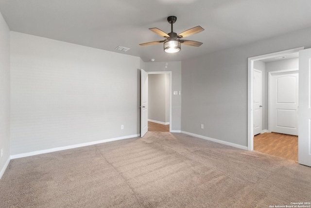 empty room featuring ceiling fan and light carpet