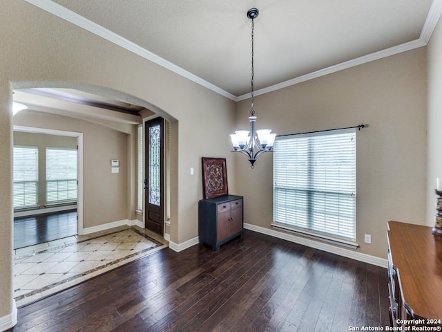 foyer entrance with dark hardwood / wood-style flooring, crown molding, plenty of natural light, and a notable chandelier