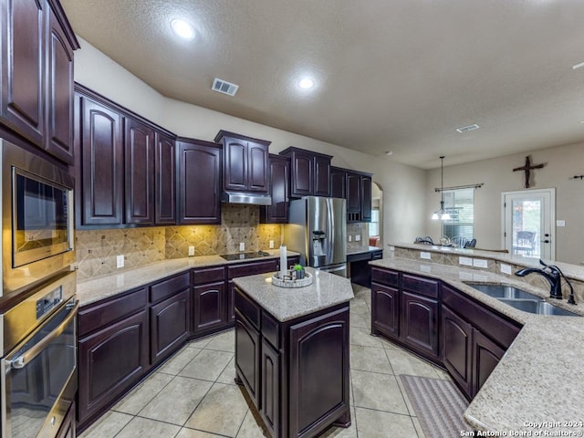 kitchen featuring stainless steel appliances, tasteful backsplash, a center island, light tile patterned flooring, and sink