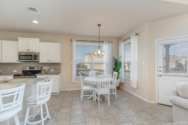 kitchen featuring white cabinetry, stainless steel appliances, tasteful backsplash, a notable chandelier, and hanging light fixtures