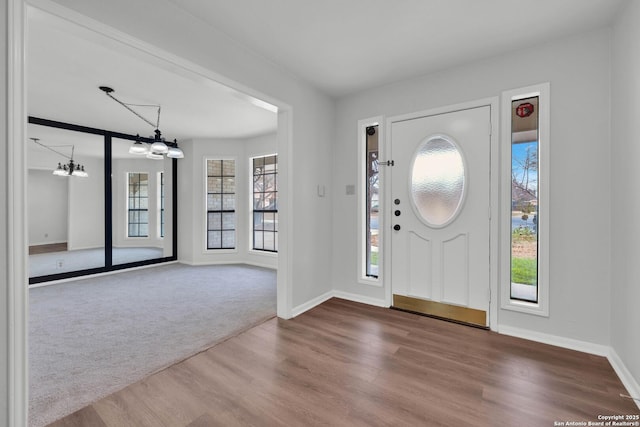 entrance foyer with a notable chandelier, a wealth of natural light, and hardwood / wood-style flooring