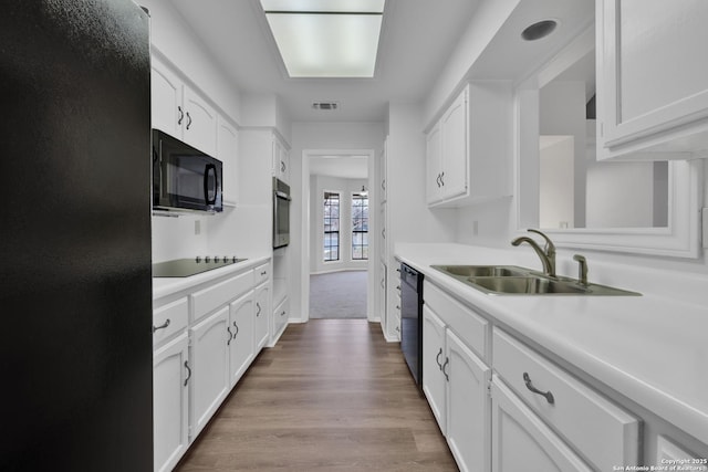 kitchen featuring sink, white cabinetry, and black appliances