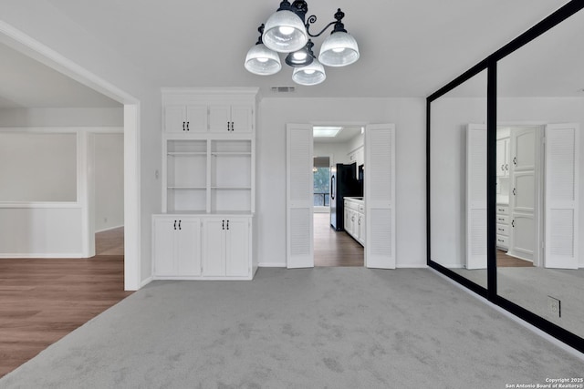 unfurnished dining area featuring a chandelier and carpet flooring