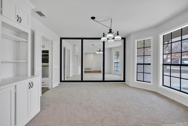 carpeted spare room with a notable chandelier and plenty of natural light