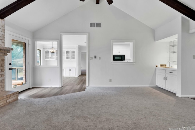 unfurnished living room with carpet floors, a fireplace, beam ceiling, high vaulted ceiling, and ceiling fan with notable chandelier