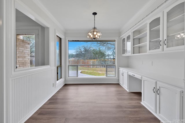 unfurnished dining area with built in desk, dark hardwood / wood-style flooring, a wealth of natural light, and a chandelier