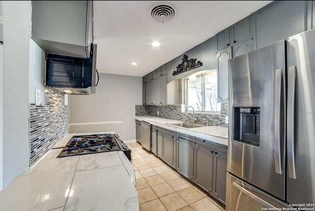 kitchen featuring stainless steel appliances, tasteful backsplash, sink, gray cabinets, and light tile patterned floors