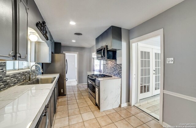 kitchen with light tile patterned flooring, appliances with stainless steel finishes, backsplash, and sink