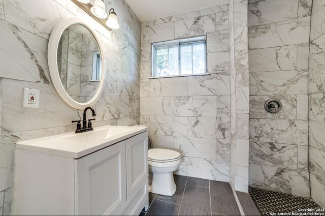 bathroom with tile walls, toilet, vanity, and tile patterned flooring