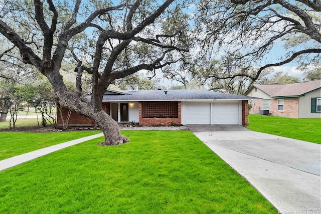 ranch-style home with a garage, cooling unit, and a front lawn