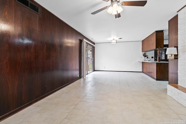 kitchen with ceiling fan, kitchen peninsula, and wooden walls