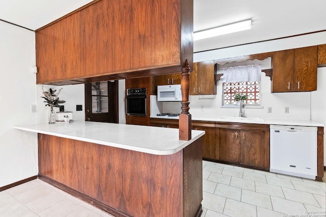 kitchen with sink, white appliances, light tile patterned floors, and kitchen peninsula